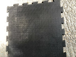 Black interlocking foam mat on a concrete floor