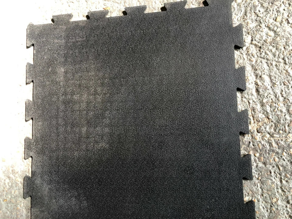 Black interlocking foam mat on a concrete floor