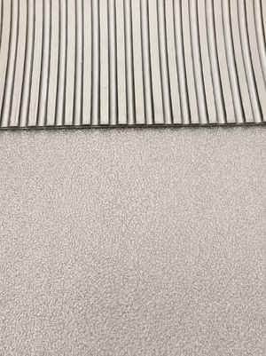 A close-up of a light gray textured material with a ribbed slatted pattern along the top edge.
