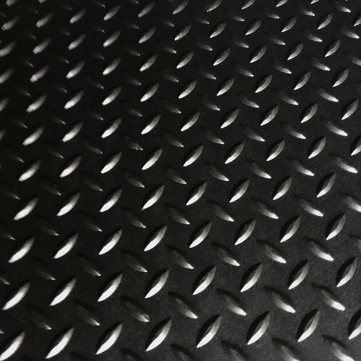 Black diamond plate textured mat with raised metallic-looking raised patterns on a dark background.