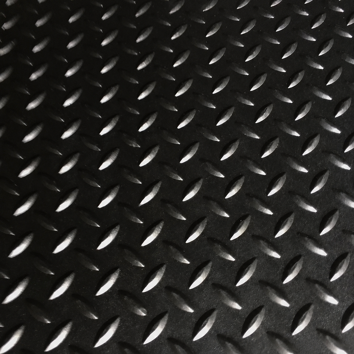 Black diamond plate textured mat with raised metallic-looking raised patterns on a dark background.