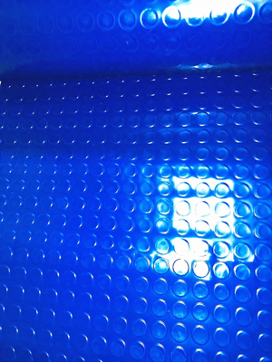 A close-up of a bright blue textured material with a repeating circular bubble or raised-dot pattern and glossy highlights.