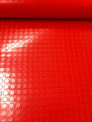 A close-up of a bright red textured surface with a repeating circular bubble or dimple pattern, likely a material or fabric swatch.