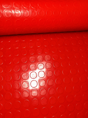 A close-up of a bright red textured surface with a repeating circular raised pattern, shown as a rolled sheet or material sample.