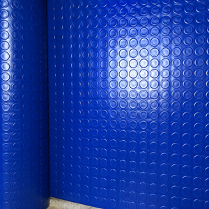 Blue textured wall panels with a repeating circular bubble pattern, shown installed in a corner with a light reflection in the center.