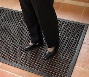 Person standing on a textured black mat with a tiled floor background