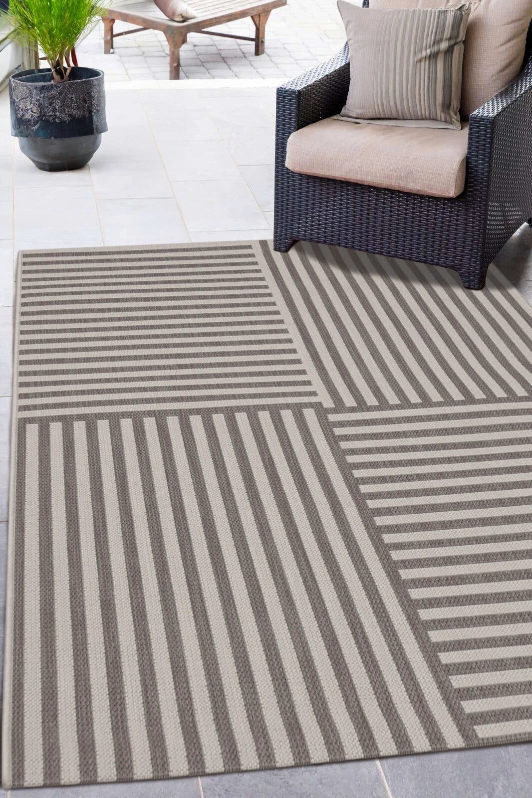 Striped outdoor rug on a patio with a chair and plant in the background