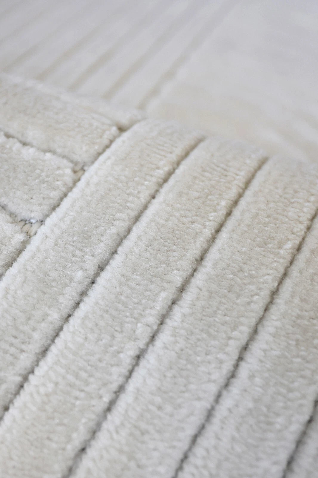 Close-up of a cream-colored textured fabric with vertical ribbed stripes.
