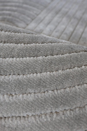 Close-up of a light gray ribbed fabric or carpet texture with stitched horizontal channels.