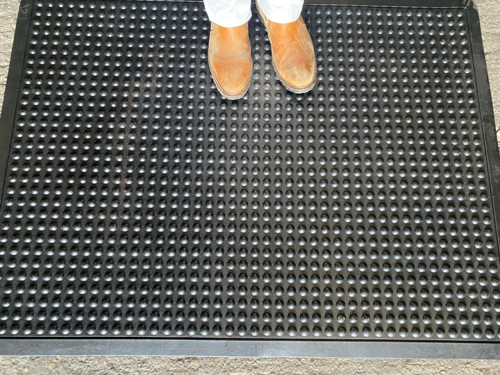 Person wearing shoes stepping onto a textured black mat