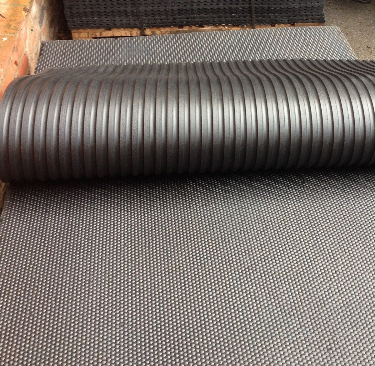 Roll of black corrugated material on a textured surface