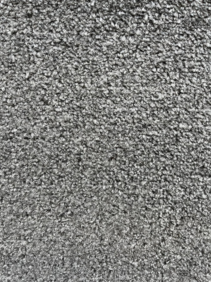 A close-up texture shot of a gray and white melange carpet or fabric, showing a dense, short-pile looped texture.