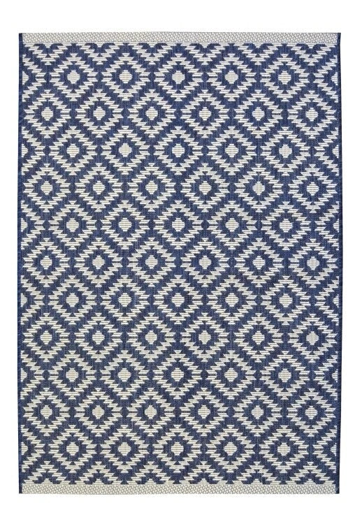 A rectangular woven rug with a repeating geometric diamond pattern in navy blue and off-white, featuring a matching off-white border.