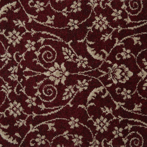 A close-up of a plush tufted rug with a deep burgundy red background and a cream-colored scrolling floral and vine pattern.