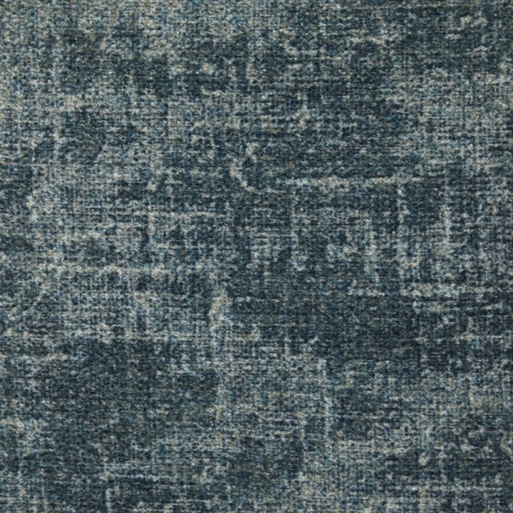 A close-up of a textured fabric or rug surface in a distressed blue-gray colorway with subtle tonal variation.