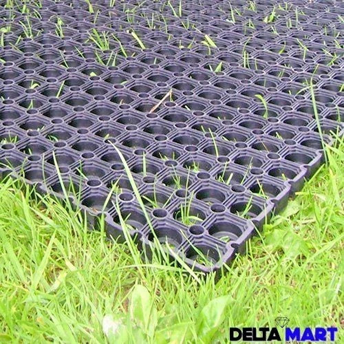 Black plastic interlocking grid mat shown on green grass, with a Delta Mart logo in the bottom right corner.