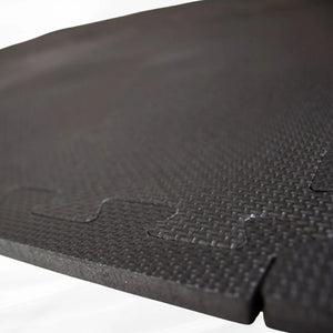 Close-up of the interlocking jigsaw mechanism on a textured black EVA foam floor mat tile.