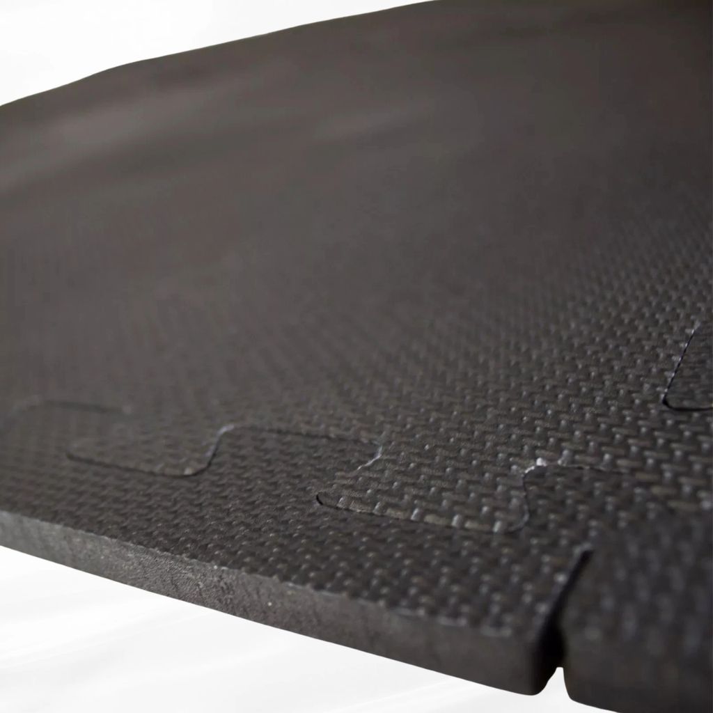 Close-up of the interlocking jigsaw mechanism on a textured black EVA foam floor mat tile.