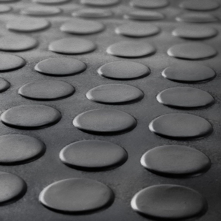 Macro close-up of the raised coin pattern texture on a black anti-slip rubber garage flooring mat.