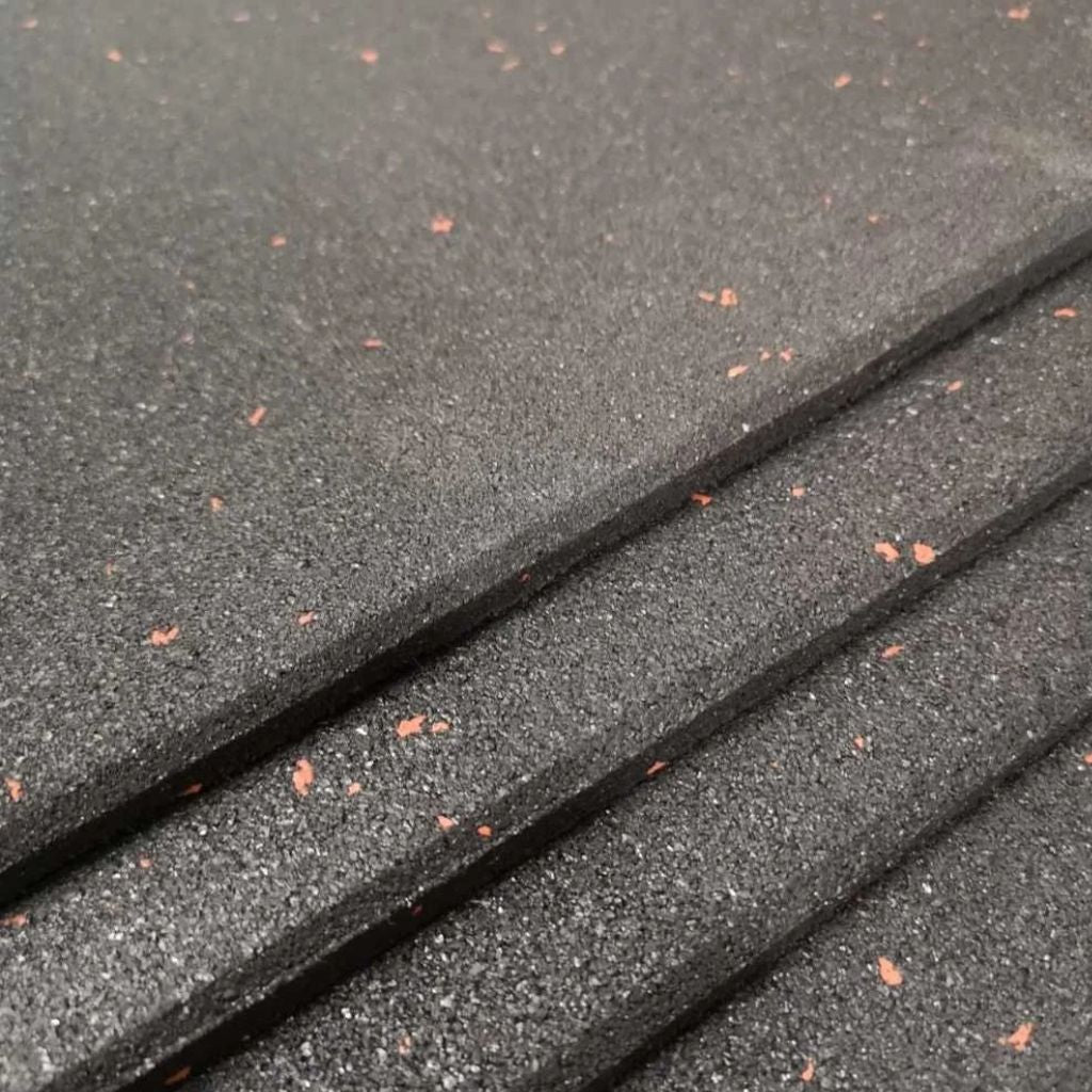 Angled close-up of stacked 10mm heavy duty fine crumb rubber gym floor tiles with burnt orange flecks.
