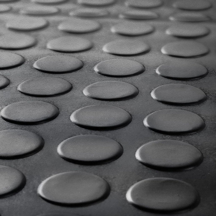 Close-up of the raised coin stud penny pattern on a black anti-slip rubber garage floor mat.