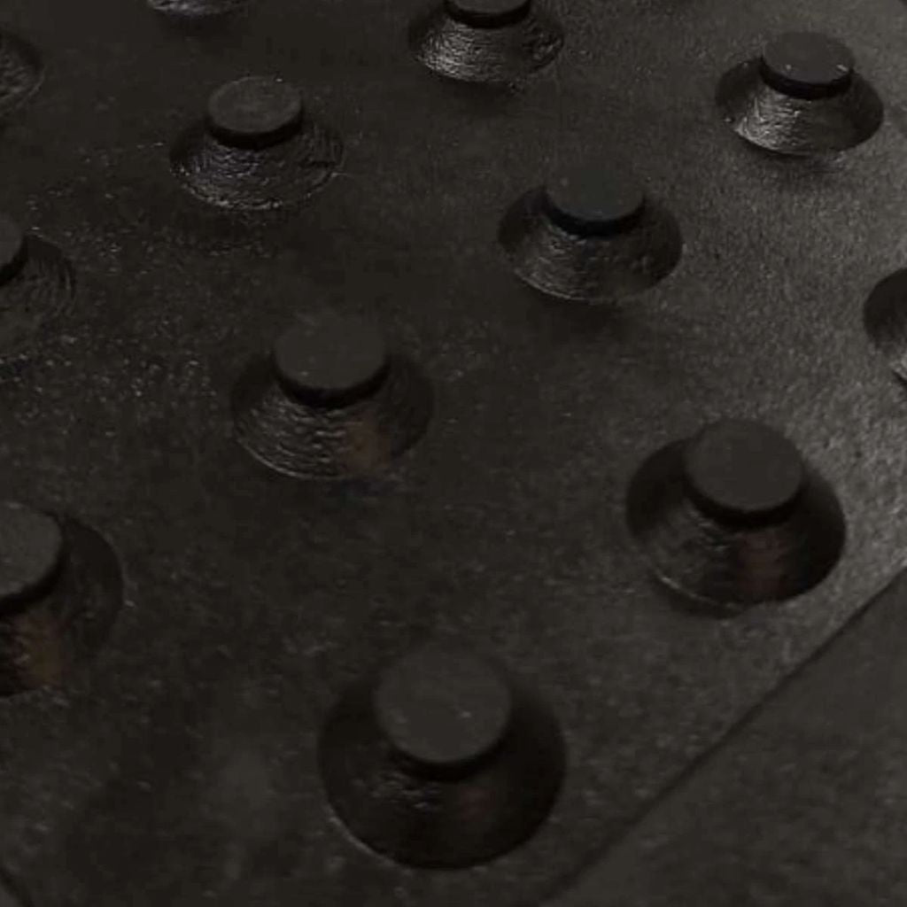 Close-up view of the heavy-duty conical rubber drainage studs on the underside of a horse stable mat.