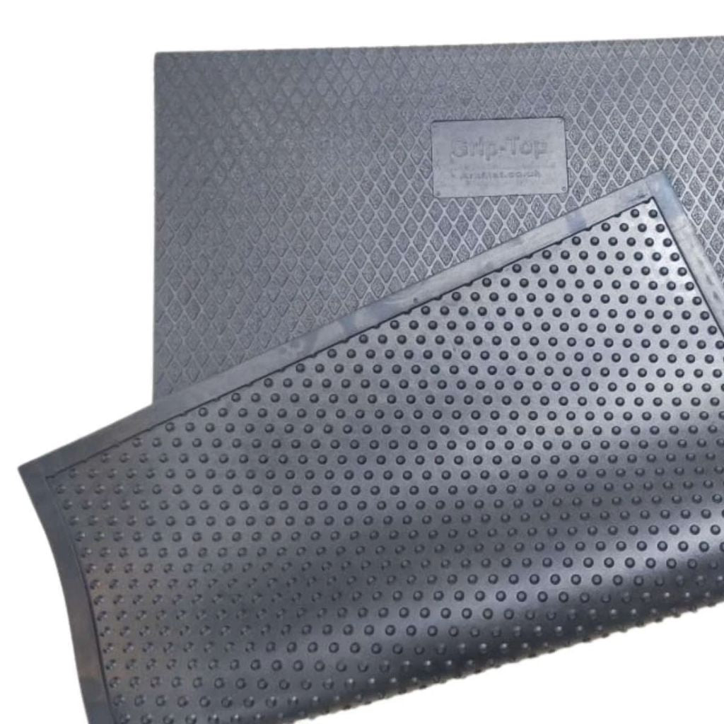 A luxury black rubber stable mat displaying the textured diamond grip top layer alongside its raised bottom drainage studs.