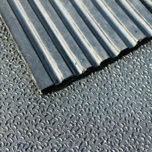 A close-up view of a 12mm thick heavy-duty rubber stable mat showing a textured amoebic finish surface layered over linear drainage grooves.