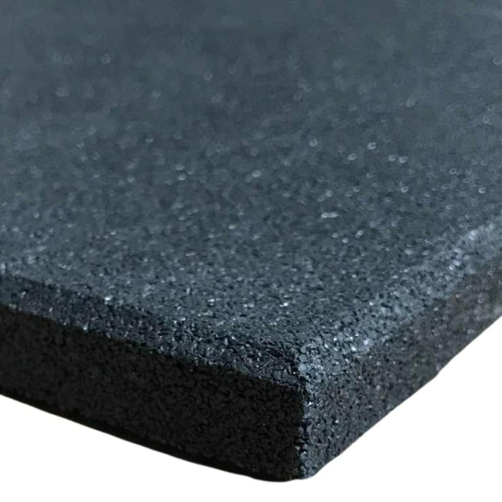 A close-up corner view of a heavy-duty black rubber gym mat floor tile showcasing its dense, shock-absorbing granular crumb texture.
