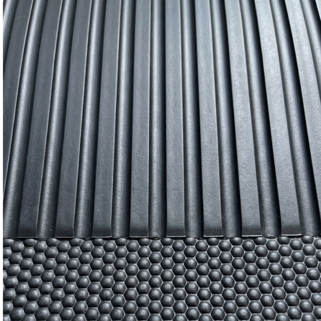 Close-up of a dark gray textured surface with vertical ridges on the upper portion and a raised honeycomb pattern across the lower portion.