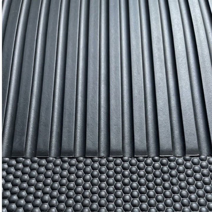 Close-up of a dark gray textured surface with vertical ridges on the upper portion and a raised honeycomb pattern across the lower portion.