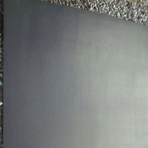 A large, flat rectangular dark gray panel or sheet of material shown from above, with gravel visible along the top and left edges.