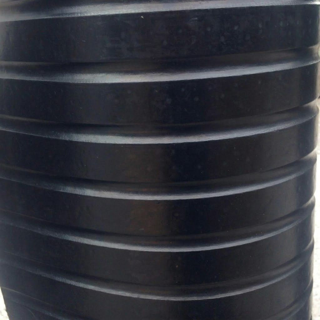 A close-up of a black ribbed plastic container or barrel, showing the textured surface and horizontal ridges.