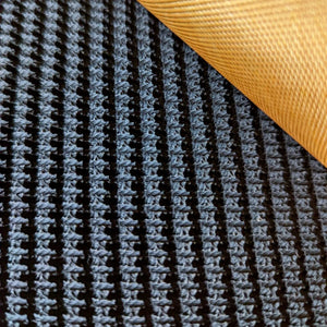 Close-up of a textured black mesh or woven mat with a rolled corner revealing a golden-yellow underside.