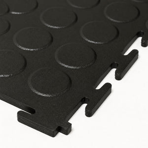 Black interlocking foam floor tiles with circular raised grips and interlocking tabs, shown on a white background.